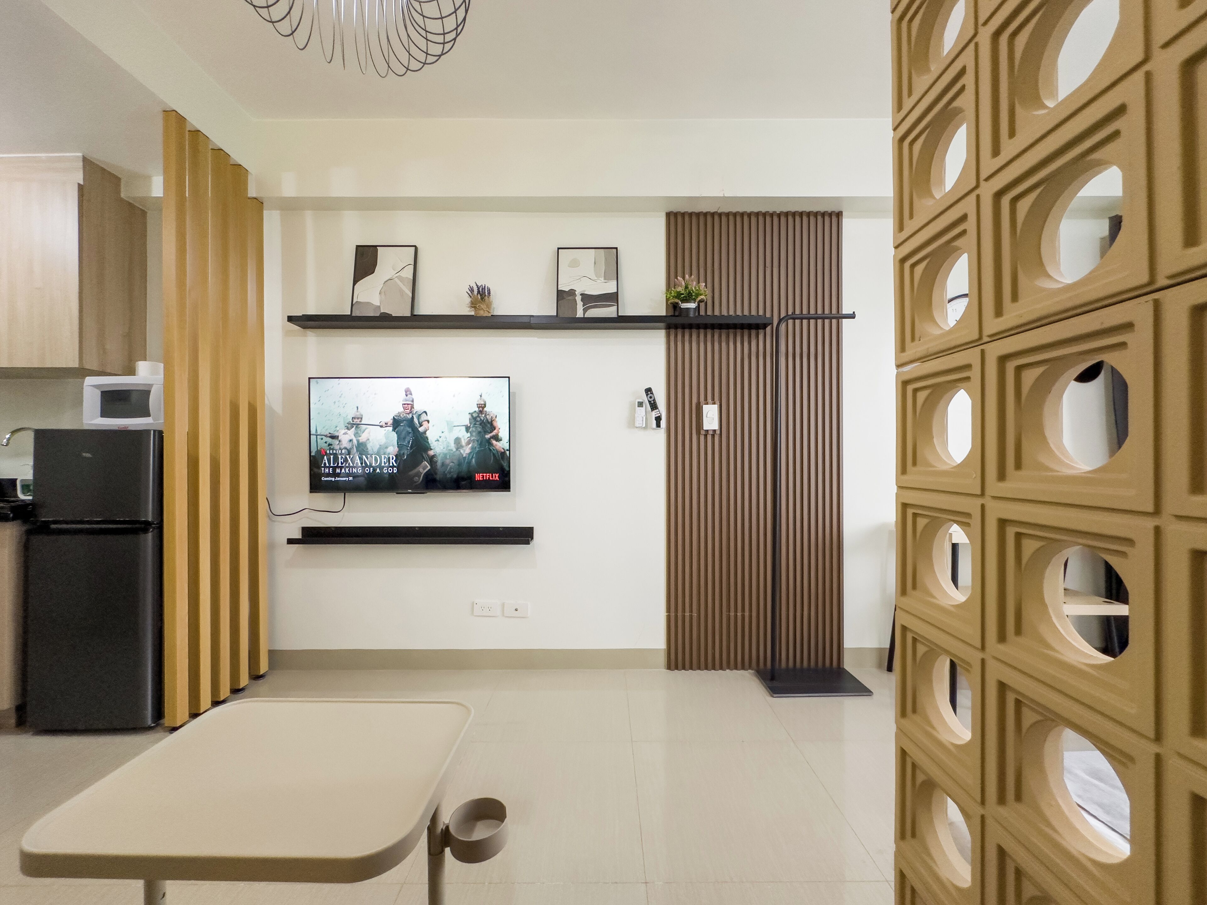 A modern kitchen with a built-in microwave, a black refrigerator, and a TV mounted on the wall.