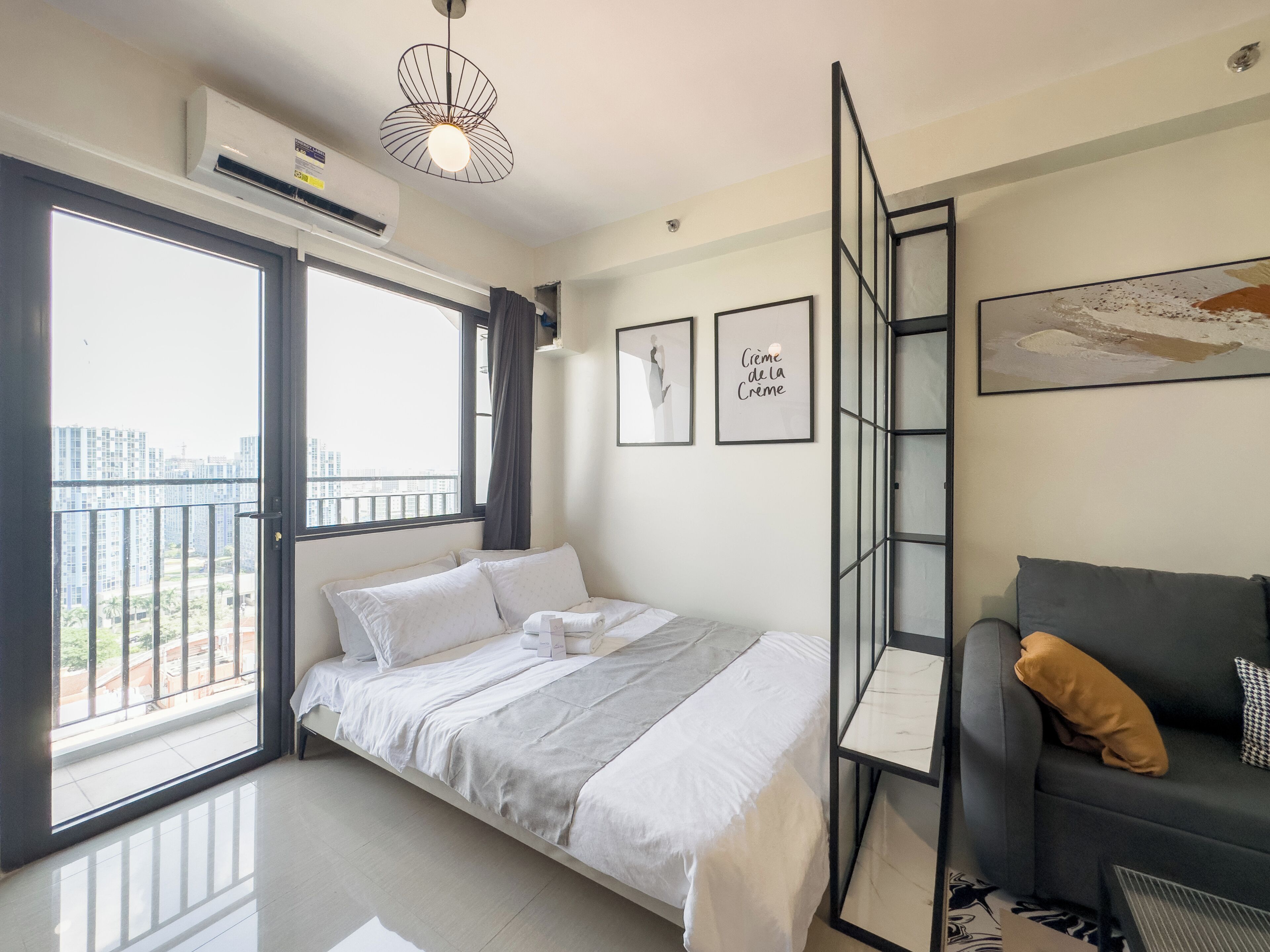 Ein modernes Schlafzimmer mit Bett, Sofa, Balkon und Blick auf die Stadt.