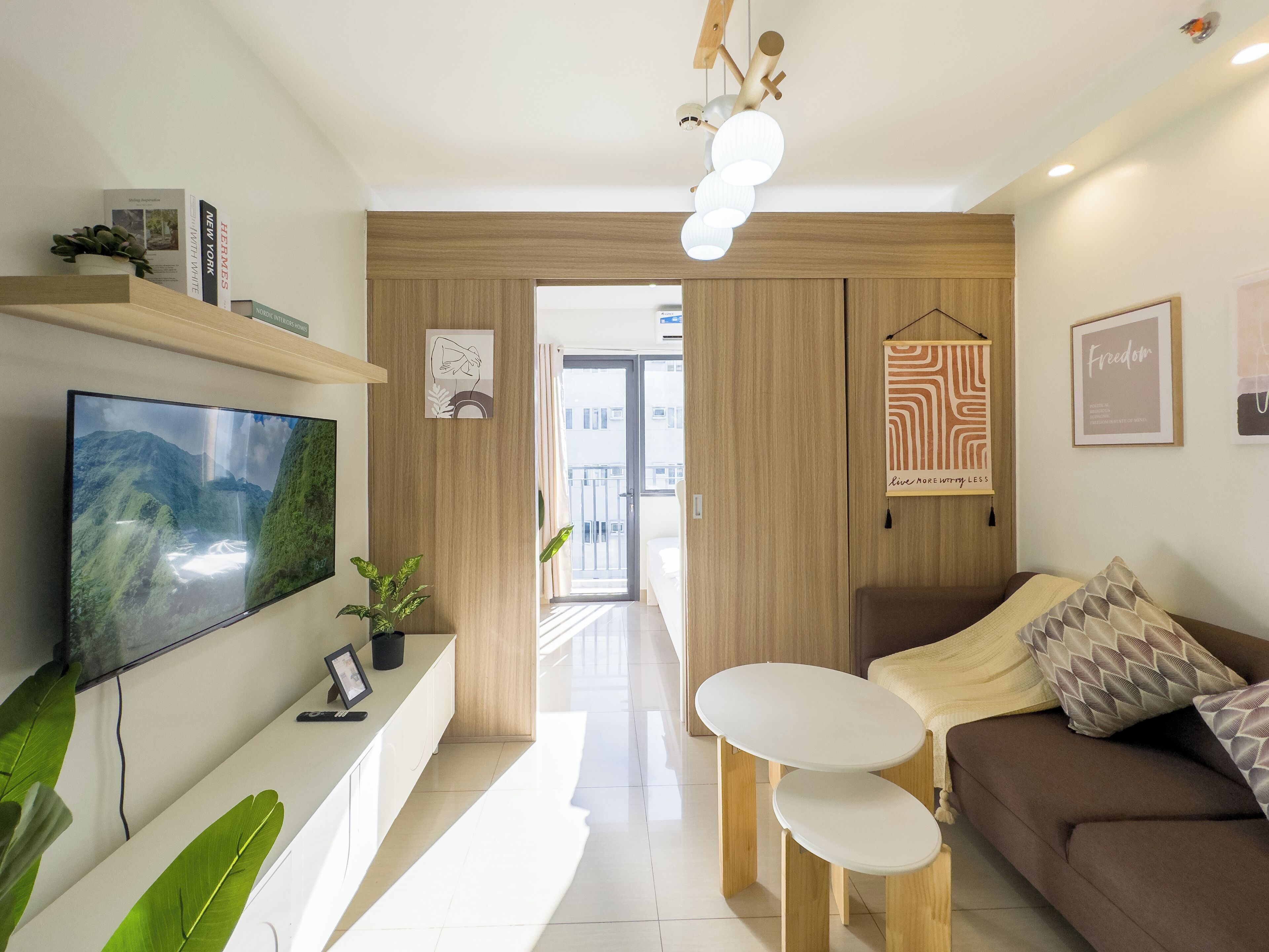 A modern living room with a flat-screen TV, a coffee table, a sofa, and a dining area.