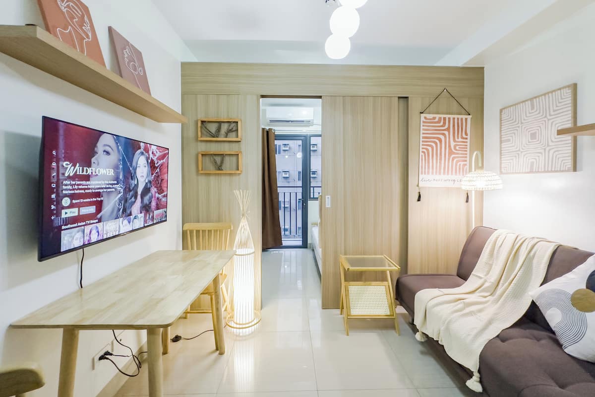 Una sala de estar moderna con televisor, muebles de madera y un sofá.