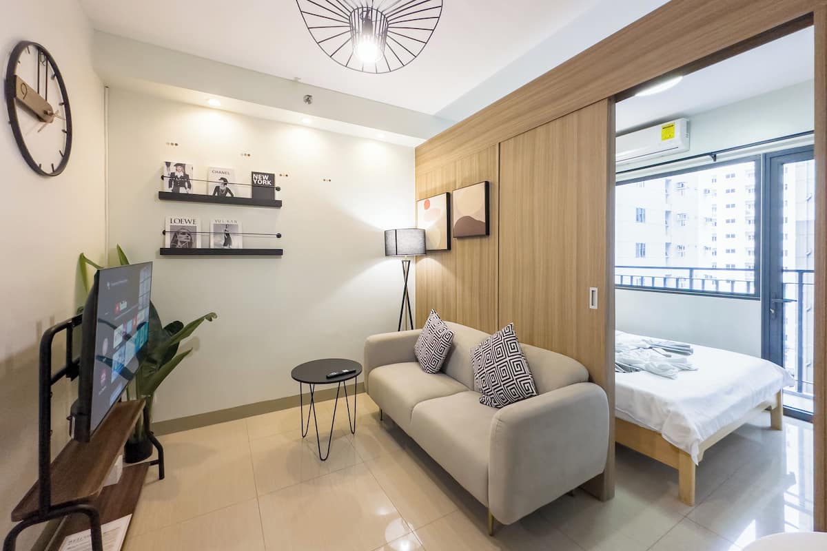 Una habitación de hotel moderna con un sofá, una mesita, un reloj y una cama con vistas a la ciudad.