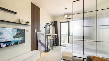 A modern living room with a flat-screen TV, a sofa, a coffee table, and a sliding glass door leading to a balcony.