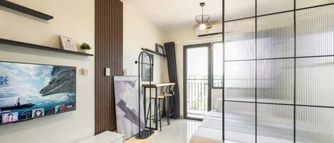 Un salon moderne doté d’un téléviseur à écran plat, d’un canapé, d’une table basse et d’une porte-fenêtre coulissante donnant sur un balcon.