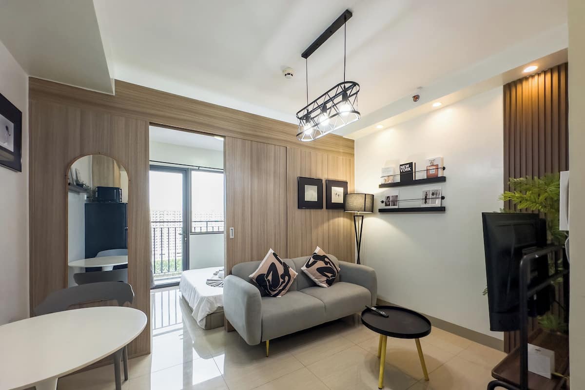 Una sala de estar moderna con un sofá gris, una mesa redonda y un mueble bajo para televisión negro.