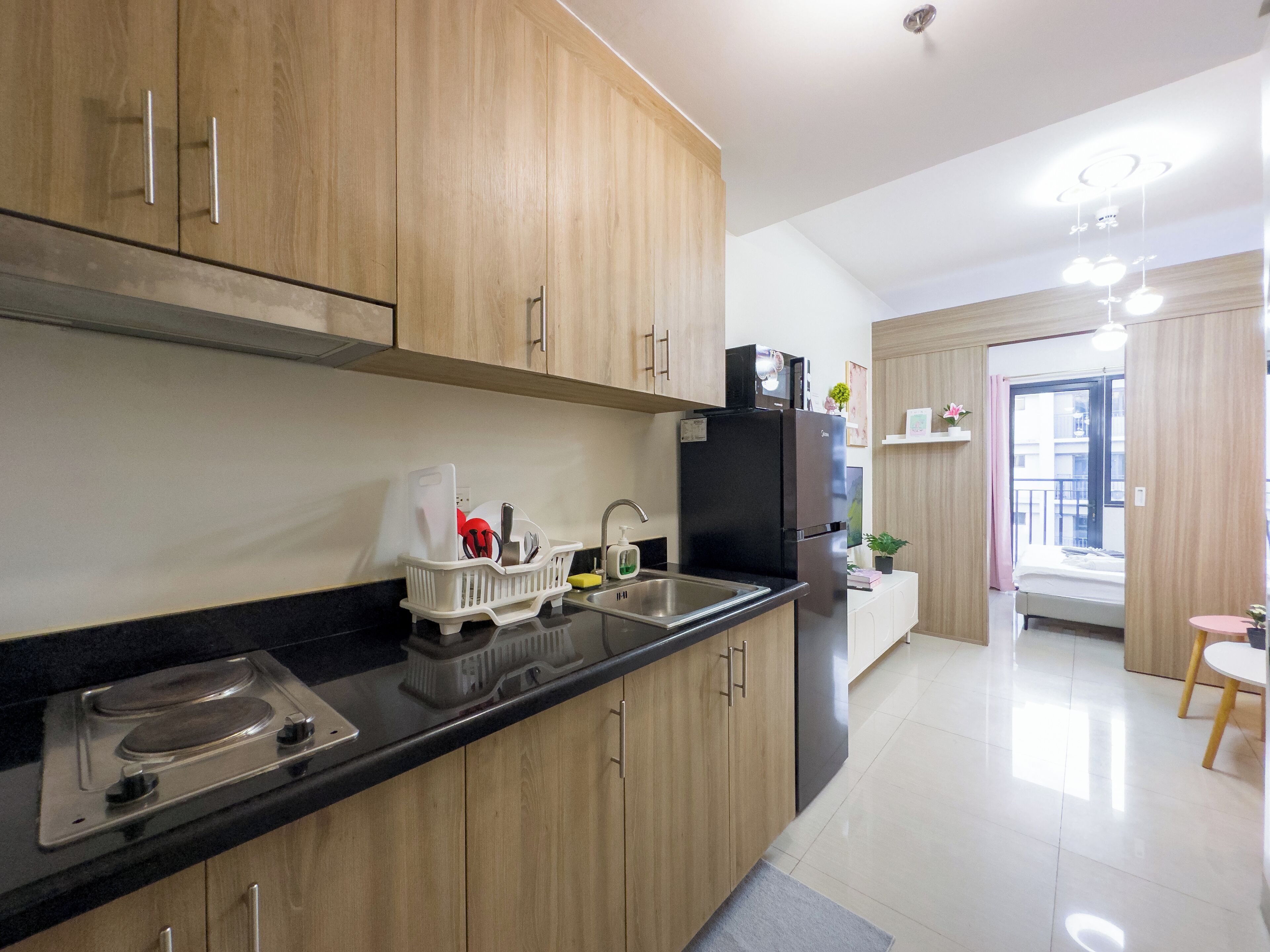 Une cuisine moderne avec des meubles en bois, un plan de travail noir et un lave-vaisselle encastré.