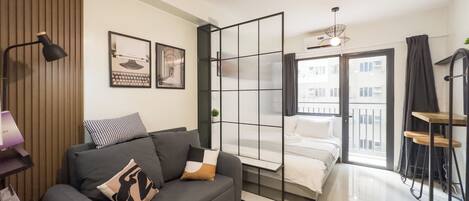 A modern living room with a sofa, a coffee table, and a bed with a view of the city.