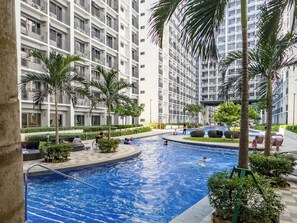A swimming pool surrounded by palm trees and modern apartment buildings.