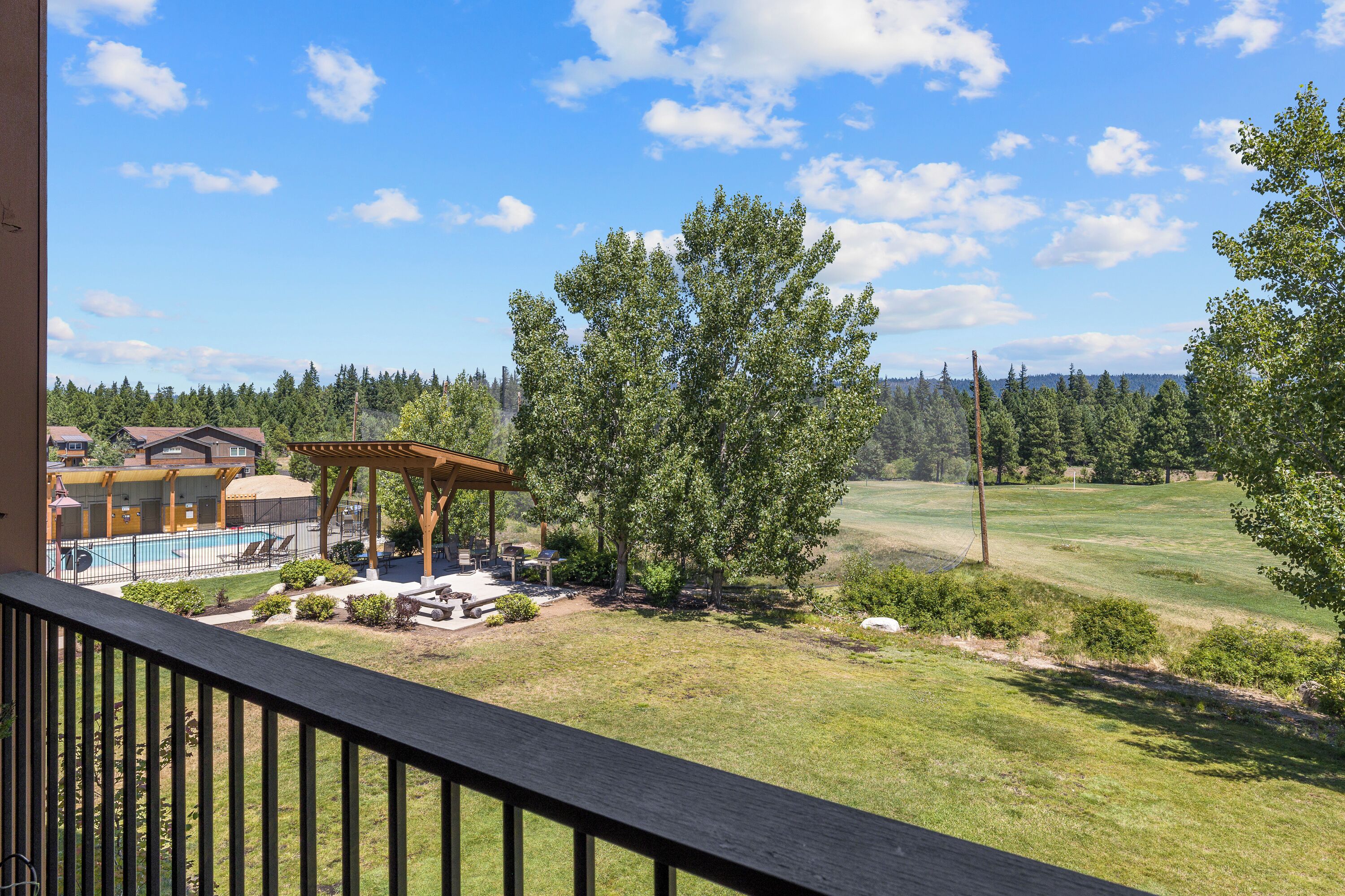 A view from a balcony overlooking a pool area, a gazebo, and a golf course.