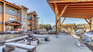 A lodge with a covered outdoor seating area, a fire pit, and barbecue grills. - Suncadia golf view condo with seasonal pool and hot tub! (Cle Elum)