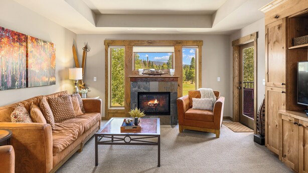 A cozy living room with a fireplace, a sofa, a coffee table, and a TV stand. - Suncadia golf view condo with seasonal pool and hot tub! (Cle Elum)