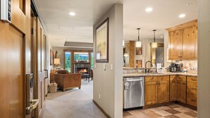 A spacious kitchen with wooden cabinets, stainless steel appliances, and a view of a living area with a fireplace. - Suncadia golf view condo with seasonal pool and hot tub! (Cle Elum)