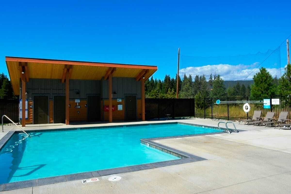 A swimming pool with a covered area and lounge chairs.
