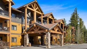 A multi-story hotel with a stone foundation, wooden balconies, and a clear sky. - Suncadia golf view condo with seasonal pool and hot tub! (Cle Elum)
