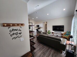 A modern living room with a sofa, TV, and a wall-mounted shelf.
