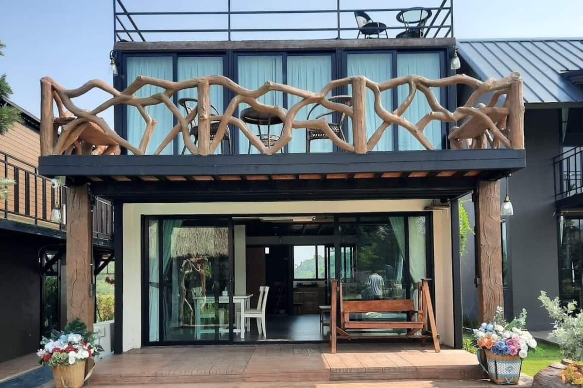 A modern building with a pool, featuring a wooden deck, outdoor seating, and a glass entrance.