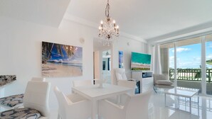 Un moderno salón con un comedor blanco, una araña y obras de arte en las paredes.