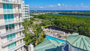Un hotel de varios pisos con balcones, piscina y vistas a un río y vegetación.