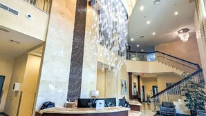 A hotel lobby with a reception desk, a staircase, and a decorative water feature.