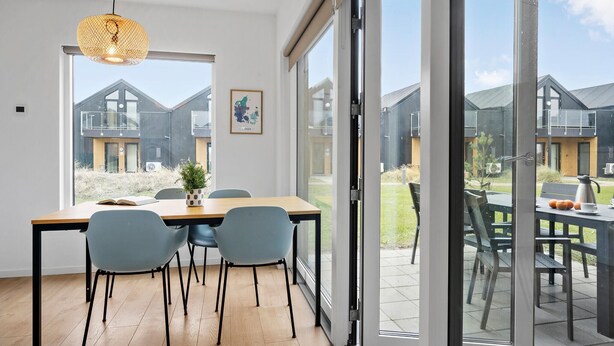 A modern dining area with a wooden table, two chairs, and a hanging light fixture. - Lovely apartment in Slagelse (Slagelse)