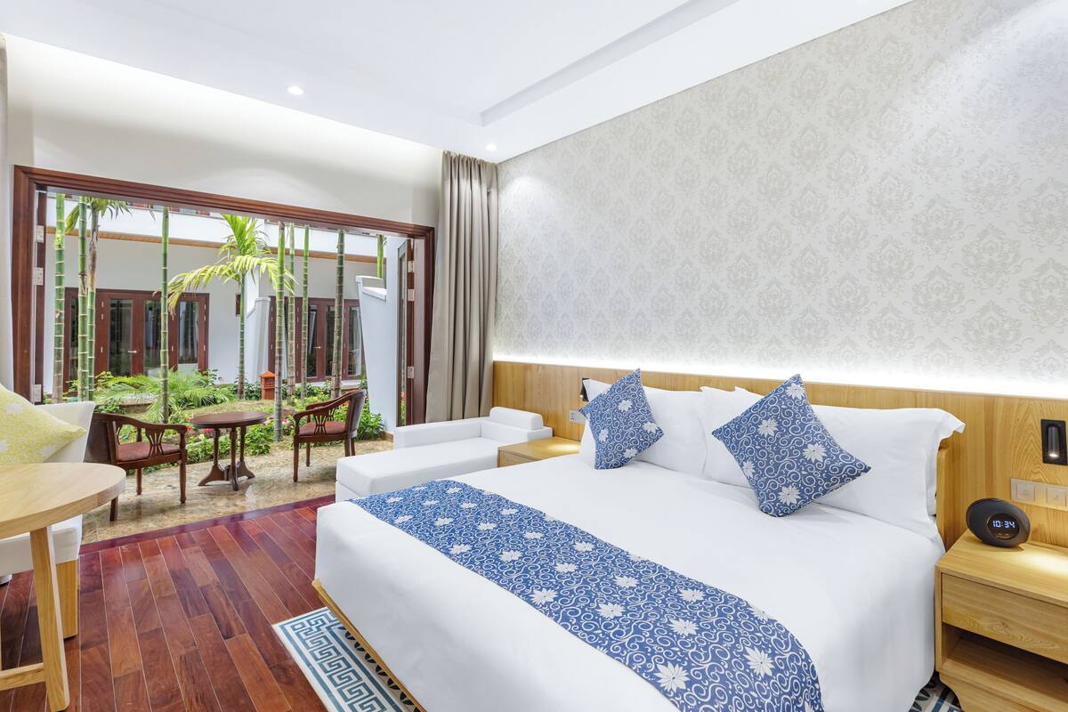 A hotel room with a large bed, a small table, and a seating area with chairs and a table.