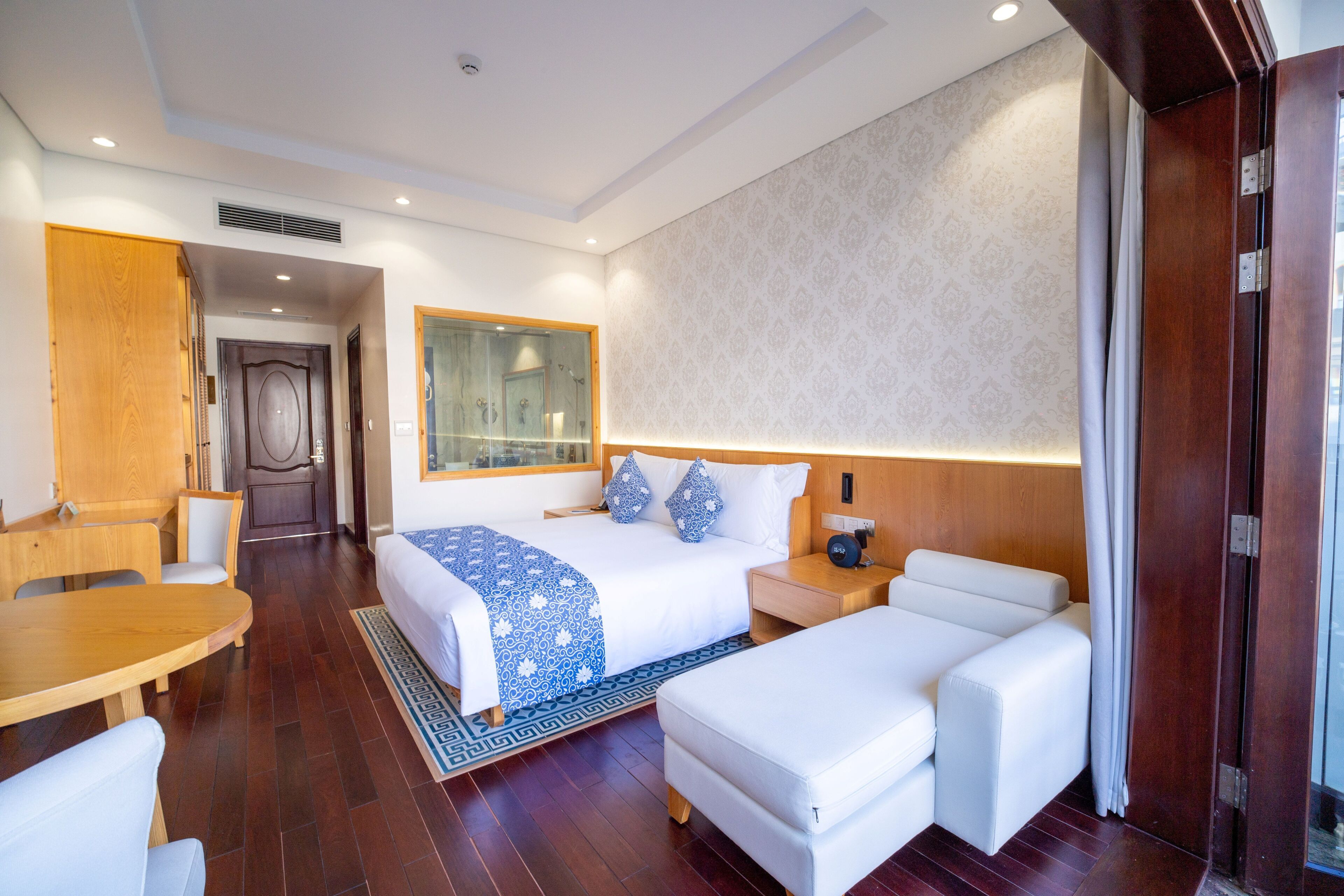 A hotel room with a bed, a desk, a chair, a sofa, and a nightstand.