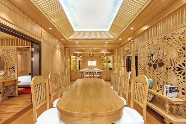 Un salón de conferencias con una mesa y sillas de madera, un techo con tragaluces y paneles decorativos de madera.