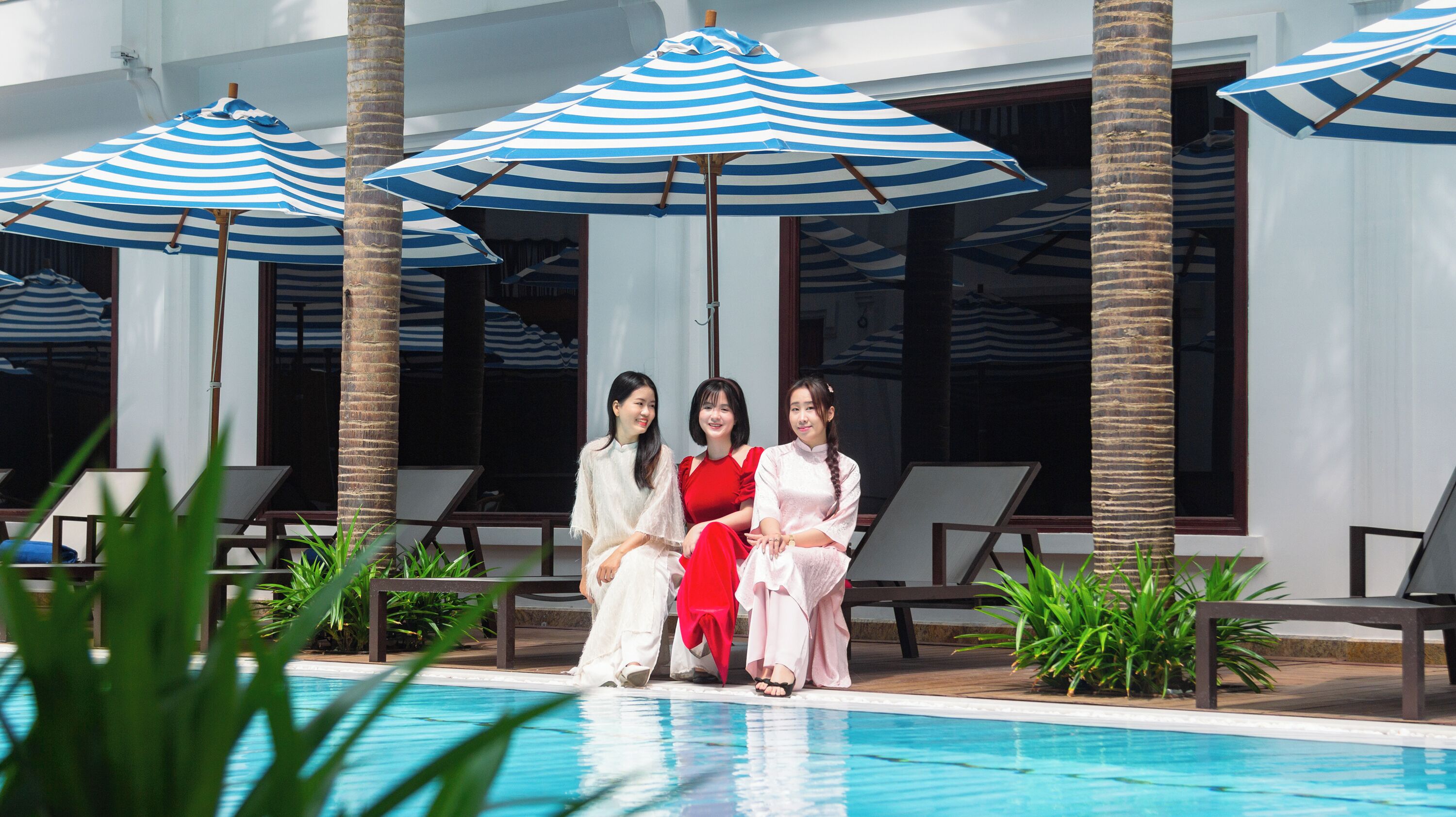 A poolside area with lounge chairs and striped umbrellas.