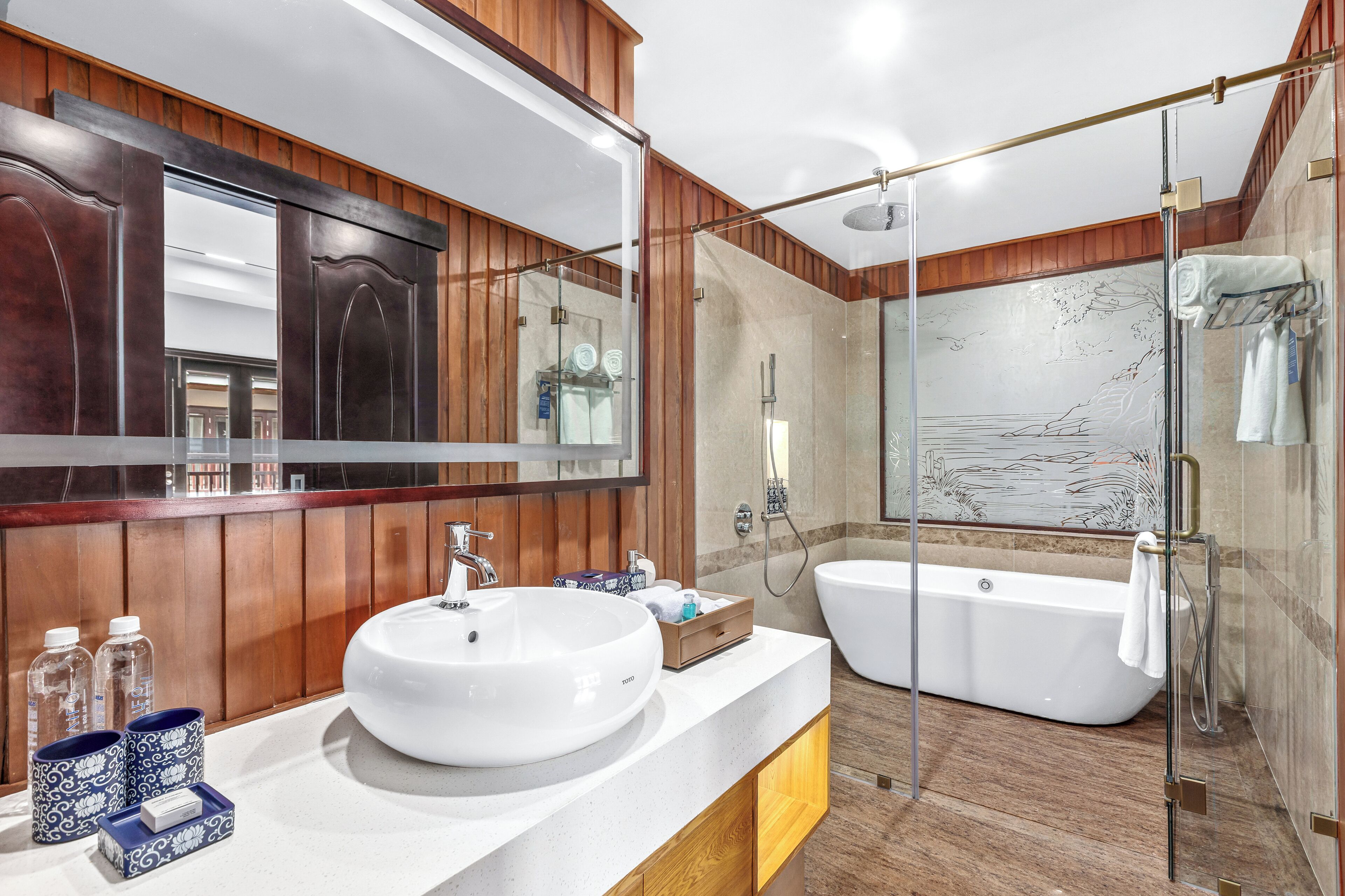 A modern bathroom with a large mirror, wooden paneling, a white sink, and a freestanding bathtub.