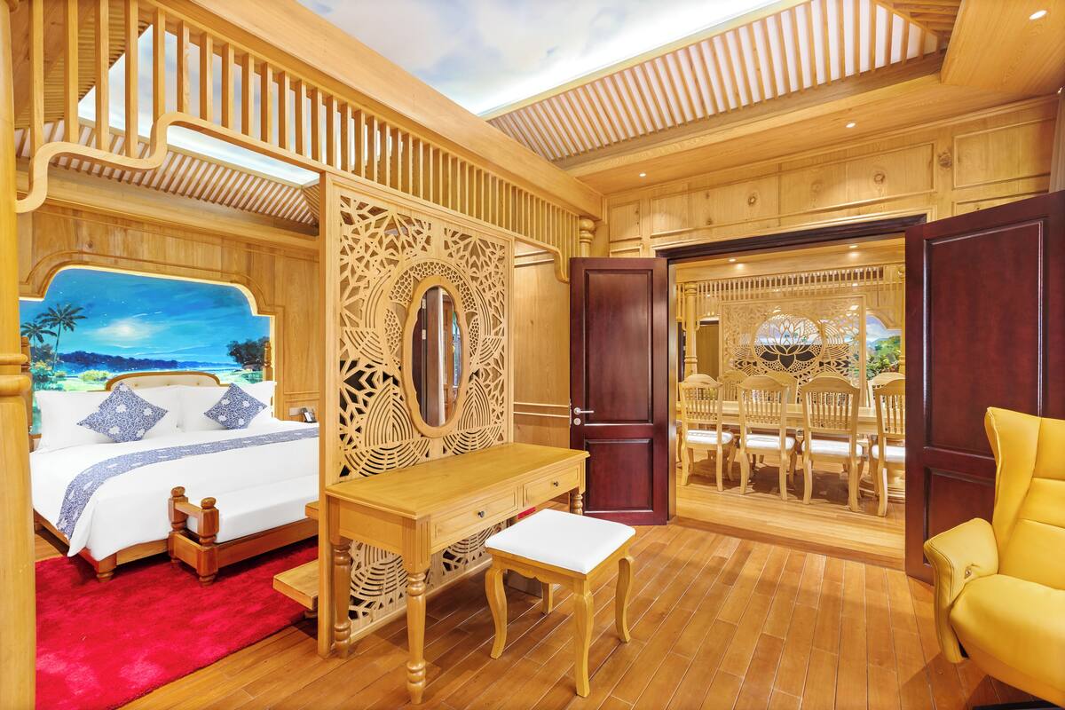 A room with a bed, a wooden desk, a chair, and a large mirror.