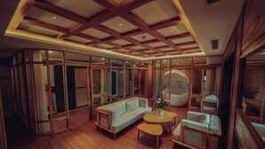 A modern interior with a wooden ceiling, a sofa, a round table, and a chair. - Wafaifo Resort Hoi An (Da Nang)