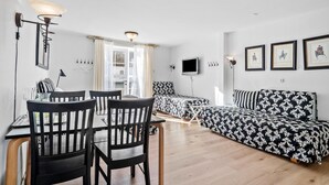 En moderne stue med spiseområde, sofa, fjernsyn og billedkunst på væggene.