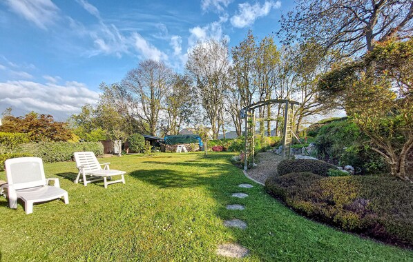 A well-maintained garden with a lawn, a wooden pergola, and two white lounge chairs. - Pet friendly home in Locquénolé with WiFi (Locquénolé)