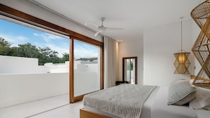 Un dormitorio moderno con una cama grande, un ventilador de techo y vistas al exterior.