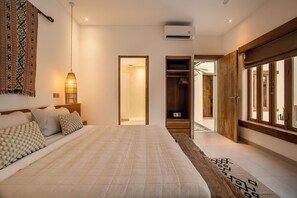 A bedroom with a large bed, a bedside lamp, a wardrobe, and a window.