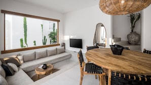 Una sala de estar moderna con un gran ventanal, una mesa de comedor de madera y un sofá.