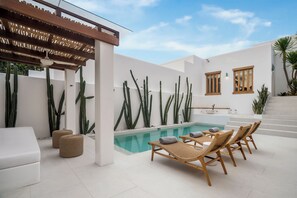 A modern outdoor pool area with lounge chairs and a pergola.