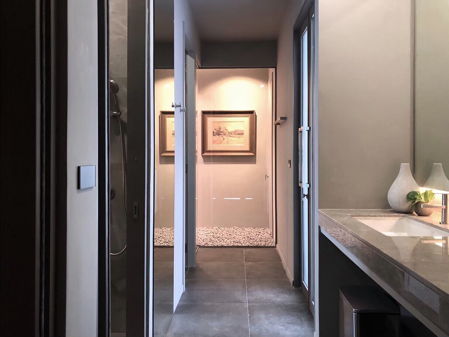 A modern bathroom with a glass shower enclosure, a sink with a vase, and a framed picture on the wall.