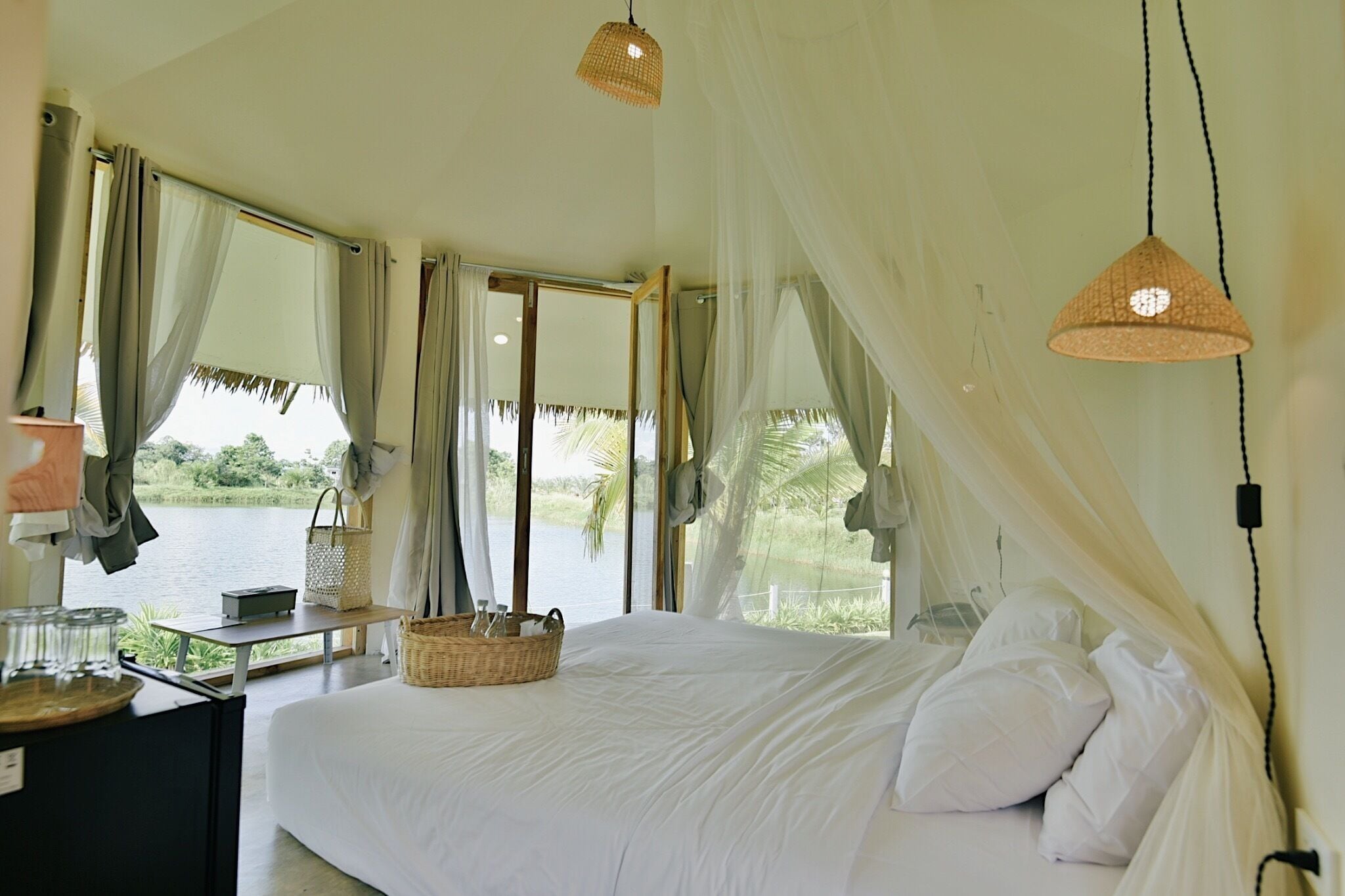 A bedroom with a bed, a bedside table, a lamp, and a view of a lake.