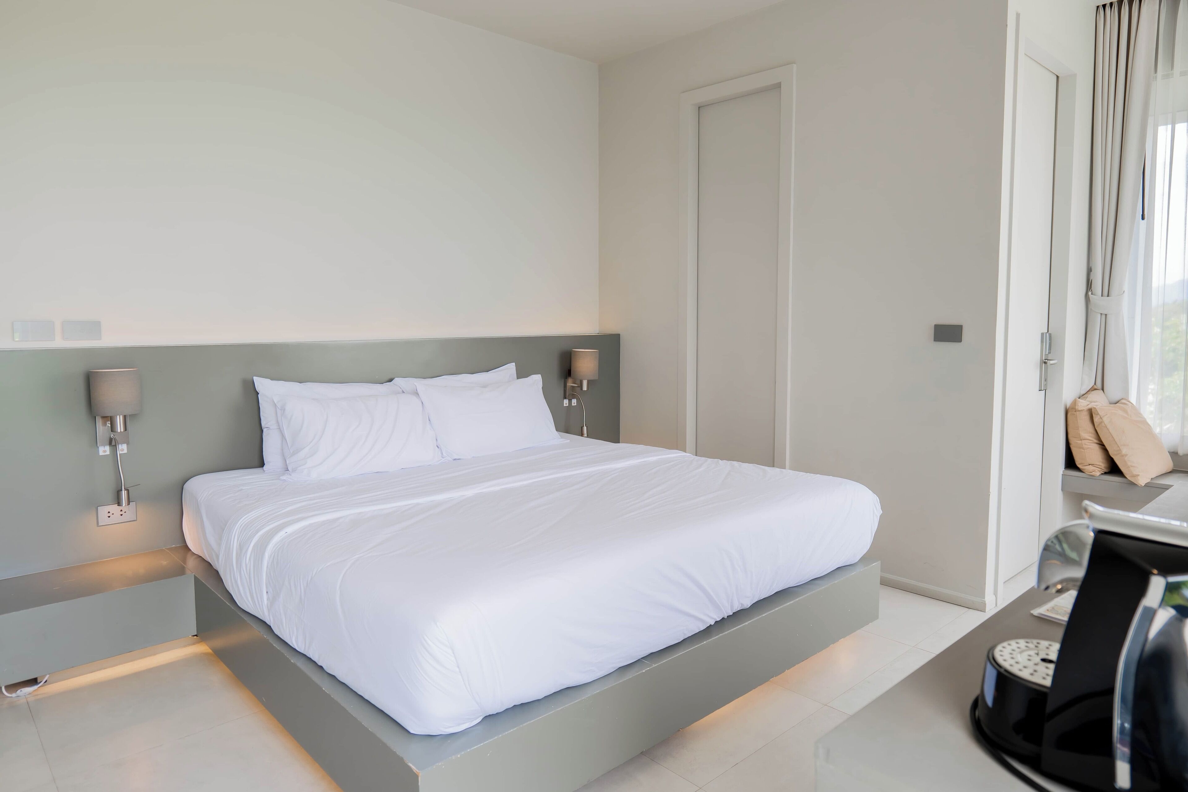 Een moderne hotelkamer met een groot bed, nachtlampjes en uitzicht op het landschap.