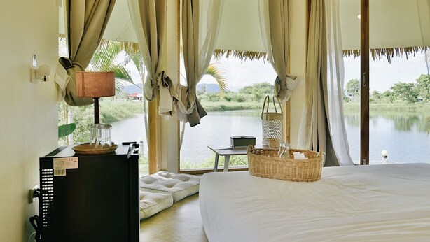 Un dormitorio con cama, escritorio, lámpara, cesta y vistas a un lago.