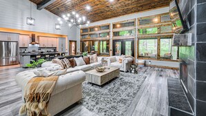 A spacious living area with a large sectional sofa, a fireplace, and a kitchen with modern appliances. - Luxe Broken Bow Vacation Rental: Hot Tub & Pets OK (Broken Bow)