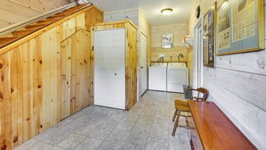 Une cuisine compacte aux murs en bois, avec une porte blanche et un petit coin repas comprenant une table et une chaise en bois.