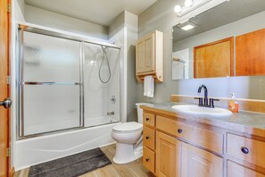 A bathroom with a glass shower enclosure, a white toilet, wooden cabinets, and a sink with a mirror above. - 24STR-00027 Fairplay Cabin w/ Mountain Views! (Fairplay)