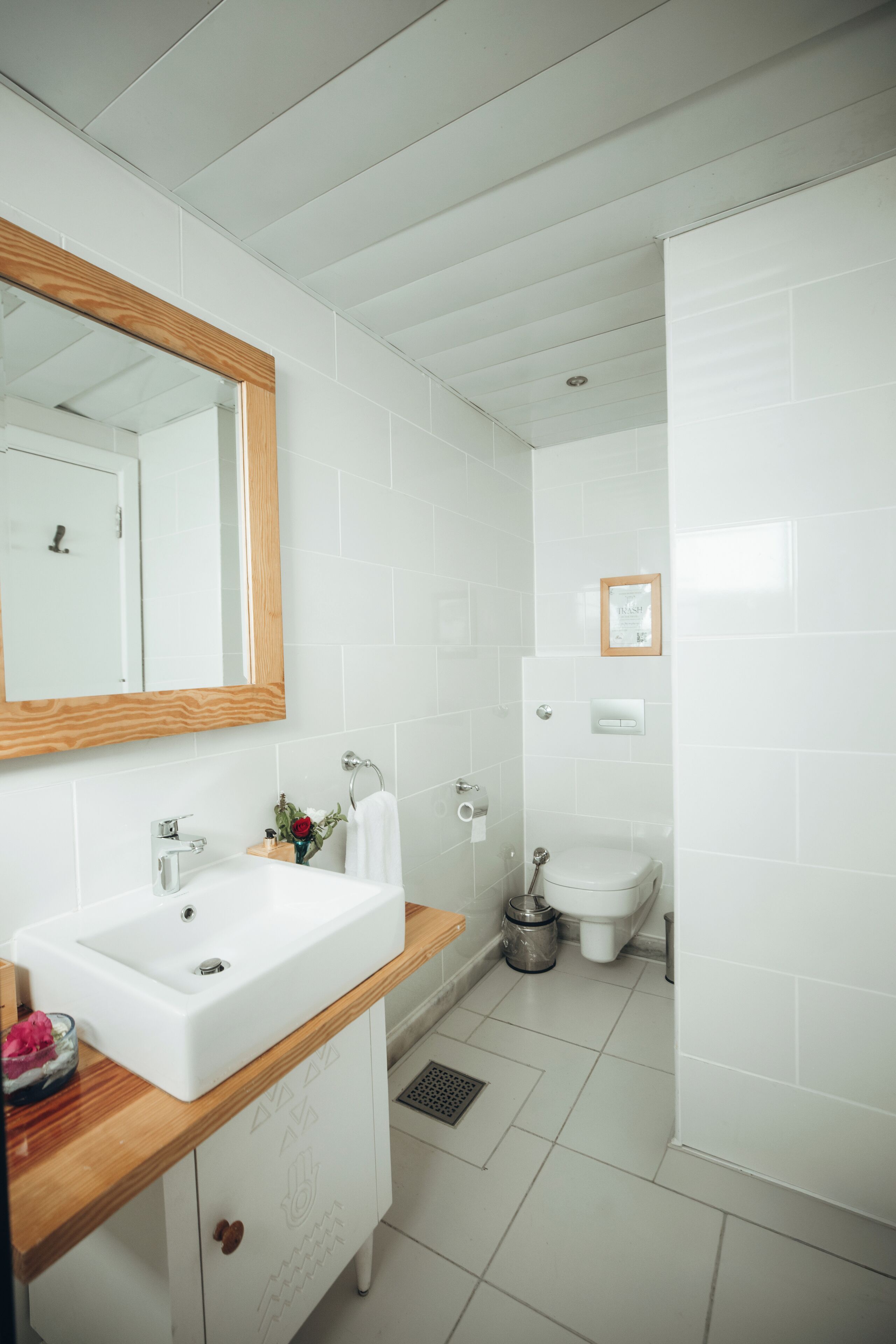 A modern bathroom with a white sink, wooden vanity, and a large mirror.