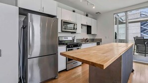 A modern kitchen with stainless steel appliances, a wooden countertop, and a view of the outside. - Vibrant Urban Loft in the Core of Little Italy (San Diego)