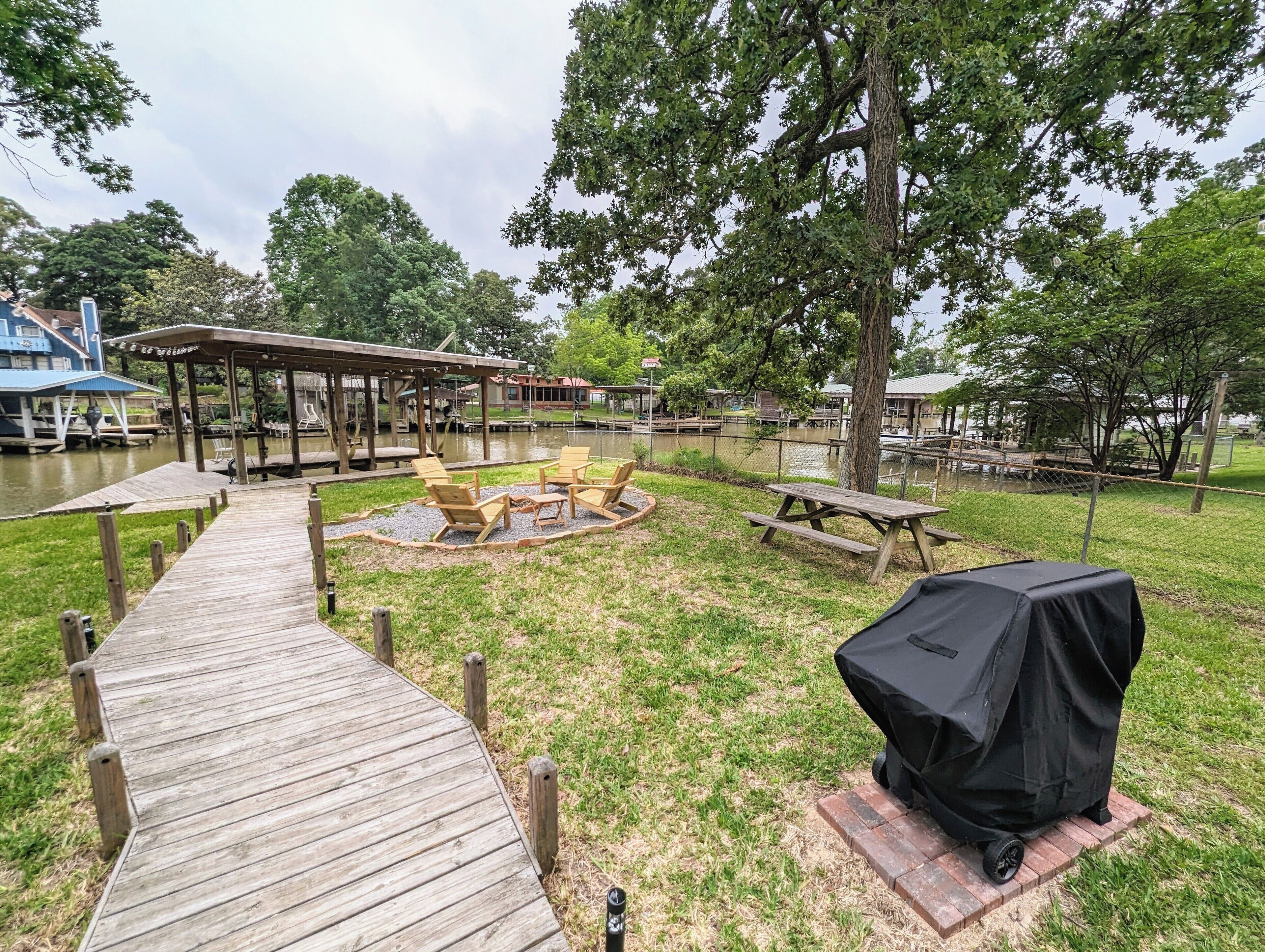 A wooden deck leading to a covered seating area with chairs and a fire pit.