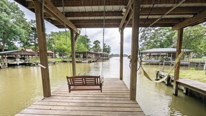 A wooden dock with a bench, wooden pillars, and a metal roof.