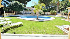 A pool area with lounge chairs, a palm tree, and a stone wall. - Bahia - spacious family villa with private pool in Moraira (Moraira)