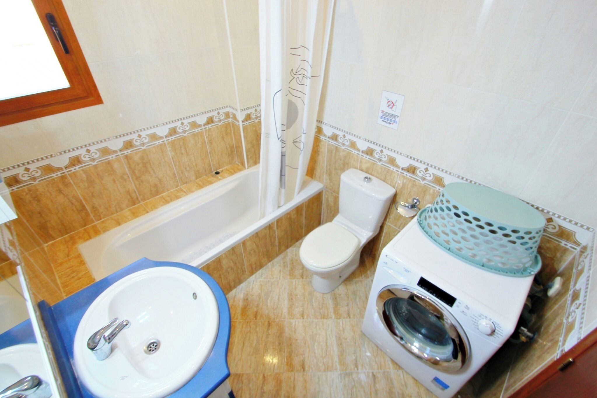 Un baño con bañera, inodoro, lavamanos y lavadora.