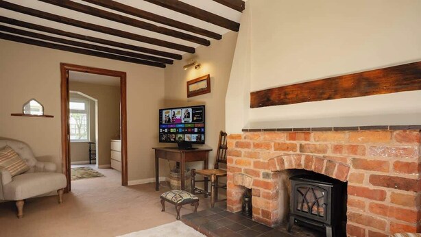 Een woonkamer met een open haard, een televisie en een bank.